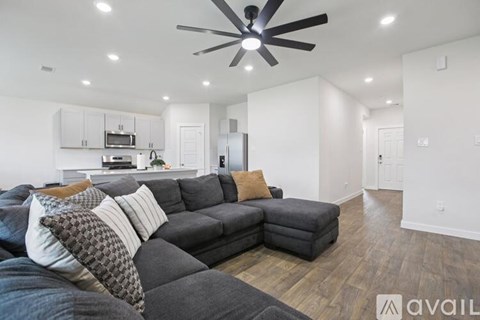A living room with a grey couch and a ceiling fan.