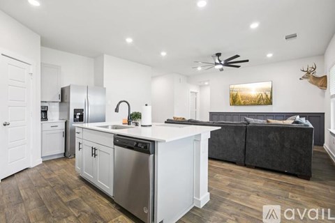 A modern kitchen with stainless steel appliances and a wooden floor.