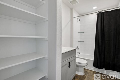 A bathroom with a toilet, sink, and a shower with a black curtain.