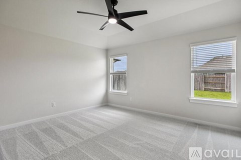 A room with a ceiling fan and two windows.