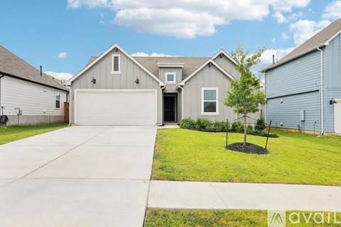 A house with a driveway and a tree in front of it.
