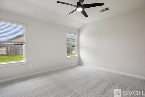 A room with a ceiling fan and two windows.