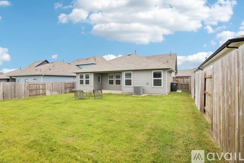 A house with a fence and a lawn in front of it.