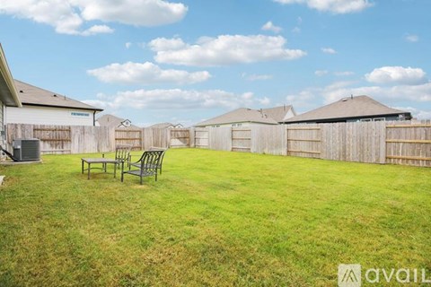 A backyard with a lawn, a bench, and a fence.
