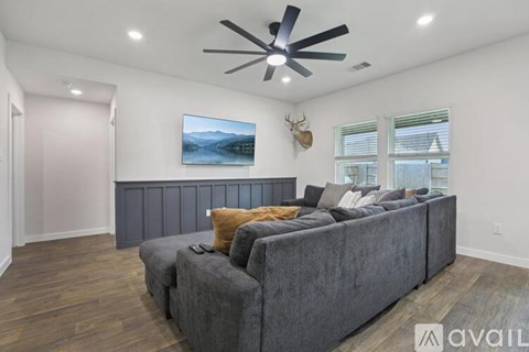A living room with a grey couch and a painting of a lake on the wall.