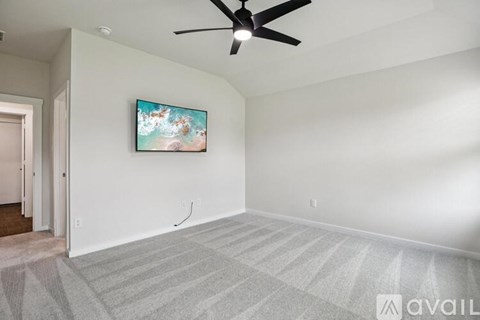 A room with a ceiling fan and a painting on the wall.
