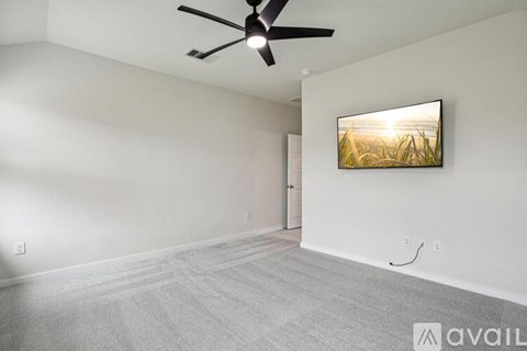 A room with a ceiling fan and a painting on the wall.