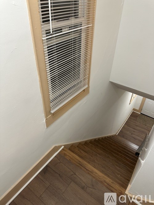 A staircase with wooden steps and a window with blinds.