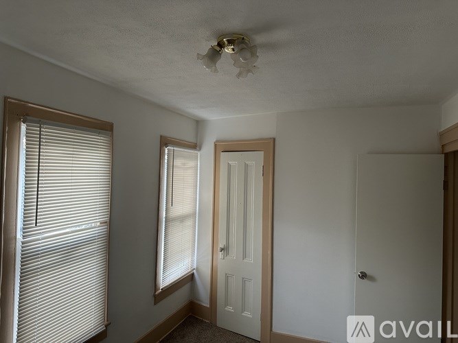 A room with a door, a window with blinds, and a ceiling fan.