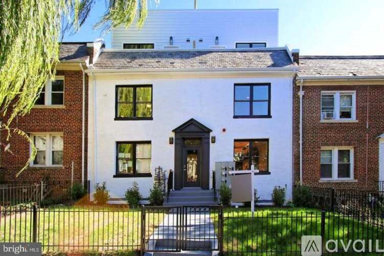 A white house with a black fence in front.