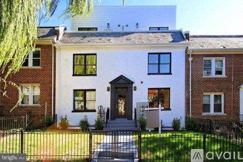 A white house with a black fence in front.