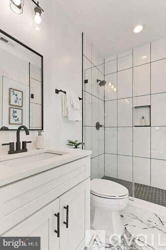 A white bathroom with a marble floor and a glass shower stall.