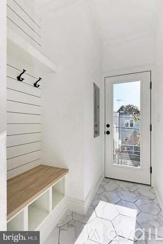 A hallway with a bench and a door leading outside.