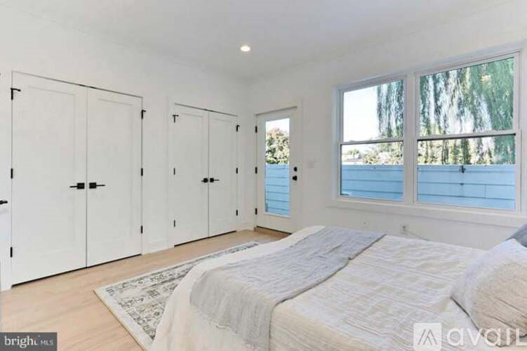 A bedroom with a large bed and a view of trees outside the window.