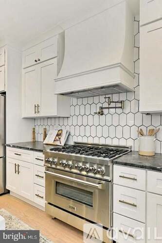 A kitchen with white cabinets and a black countertop.
