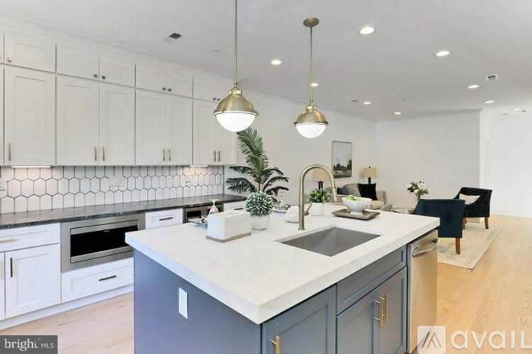 A kitchen with a large island and pendant lights.
