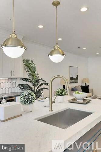 A modern kitchen with a sink, potted plants, and pendant lights.
