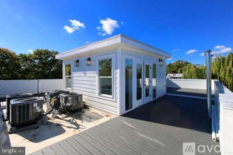 A small white house with a deck and two air conditioning units.