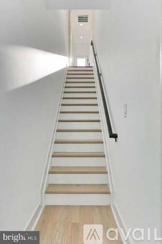 A staircase with wooden steps and a black handrail.