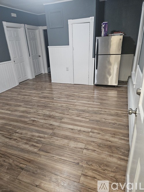 A kitchen with a wooden floor and a stainless steel refrigerator.