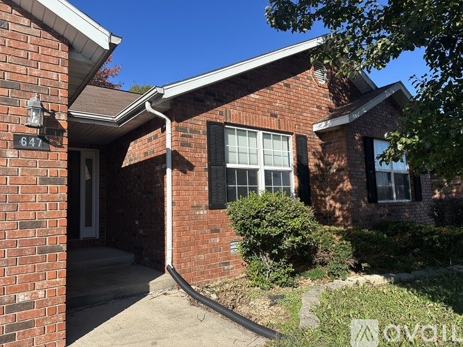 A house numbered 647 with a white door and a window with black shutters.