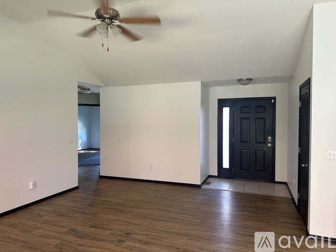 A room with a ceiling fan and wooden flooring.