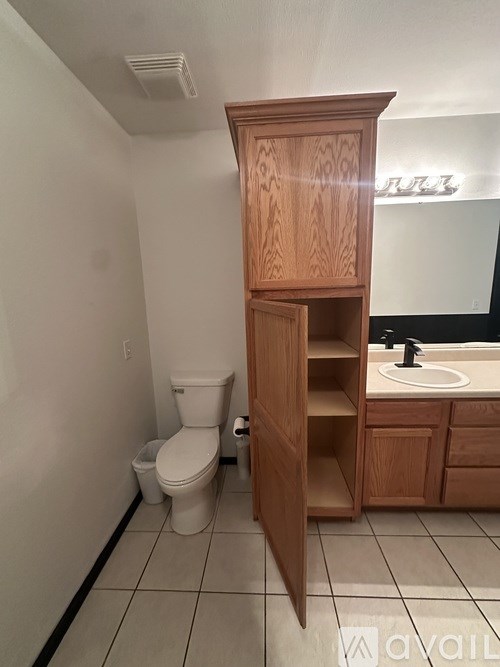 A bathroom with a toilet, sink, and wooden cabinet.