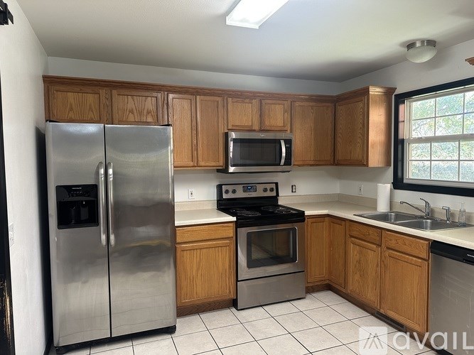 A kitchen with wooden cabinets and a stainless steel refrigerator.