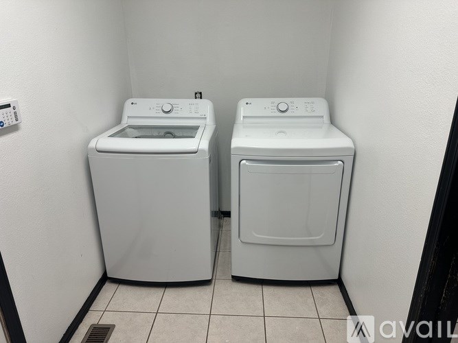 Two white front loading washing machines in a small laundry room.