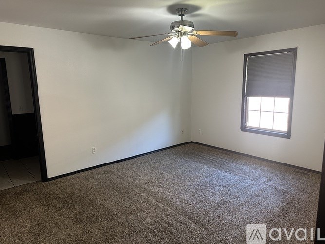 A room with a ceiling fan and a window.