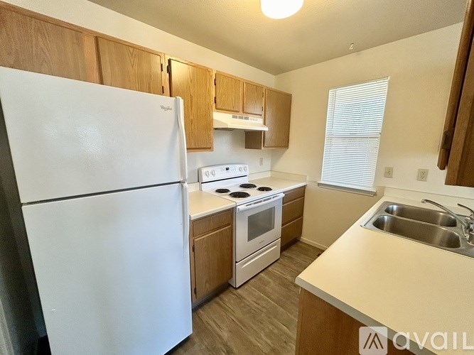 A kitchen with a white fridge, stove, and sink.