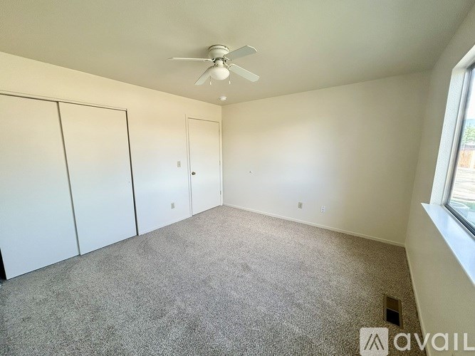 A room with a ceiling fan and three closets.