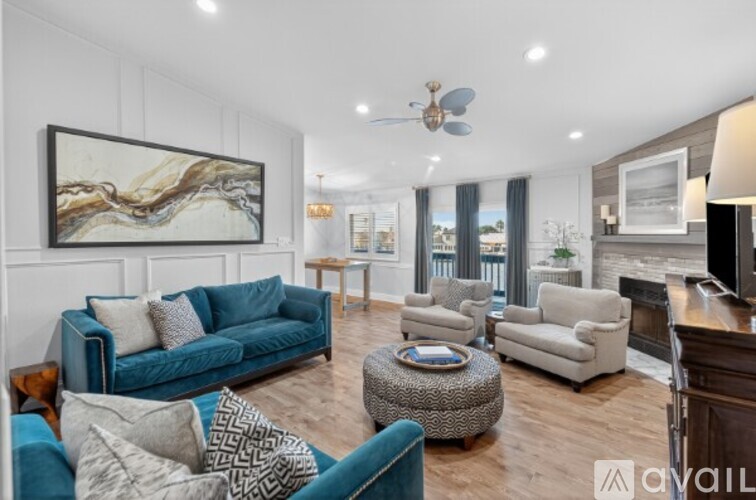 A living room with a blue couch and a painting on the wall.