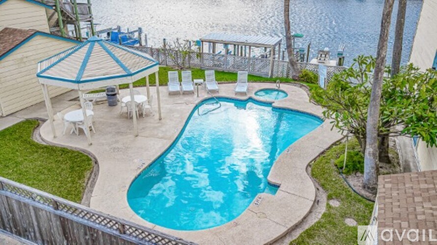 A small pool with a blue umbrella and chairs.