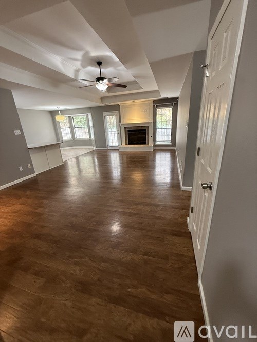 A spacious room with wooden floors and a ceiling fan.