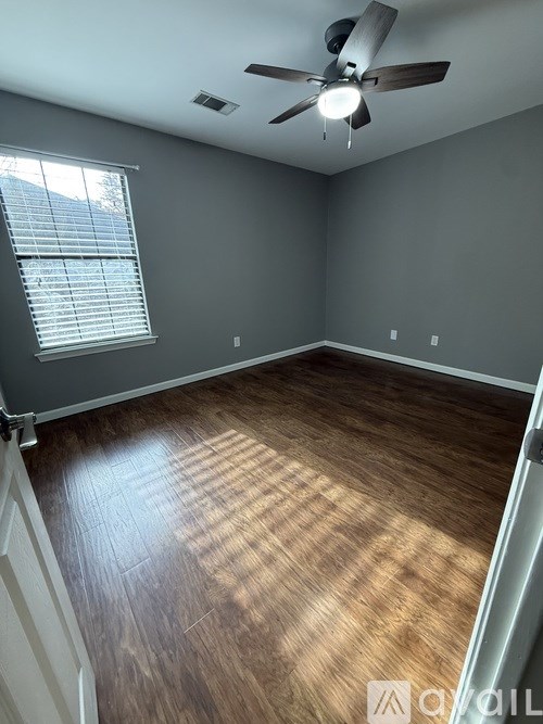 A room with a ceiling fan and wooden flooring.