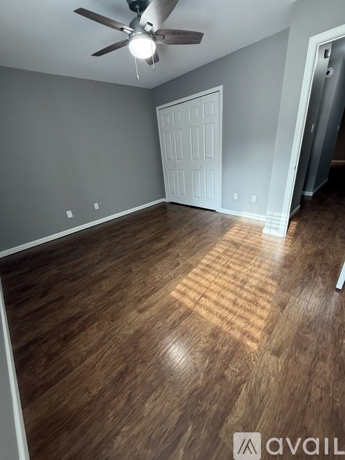 A room with a ceiling fan and wooden flooring.