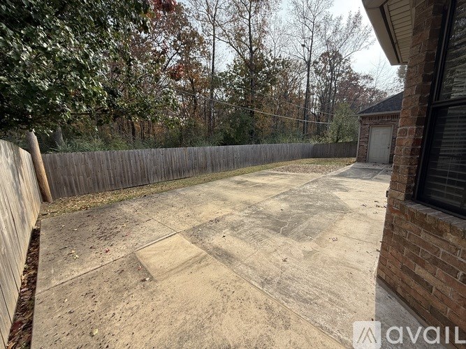 A backyard with a wooden fence and a concrete patio.