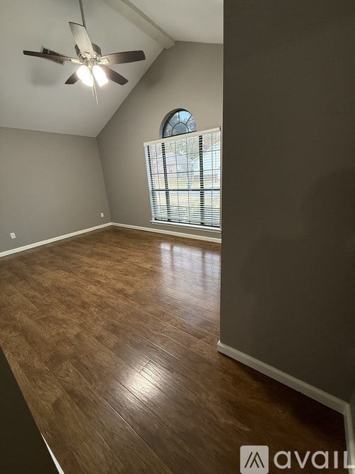 A room with a ceiling fan and wooden flooring.