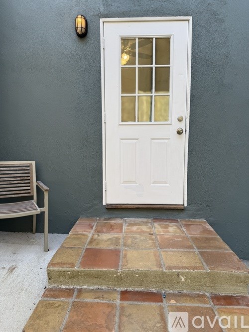 A white door with a glass window is set in a grey wall.