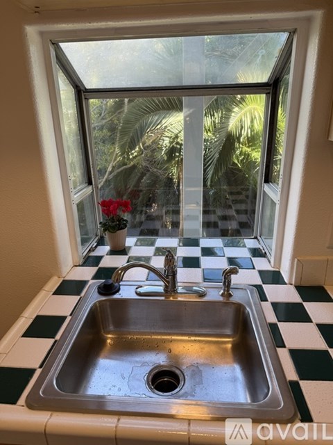 A kitchen sink with a window overlooking a green landscape.