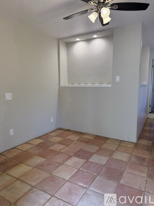 A room with a ceiling fan and tiled floor.