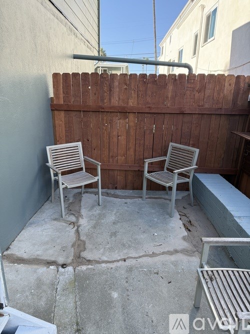 Two metal chairs and a bench are on a patio.