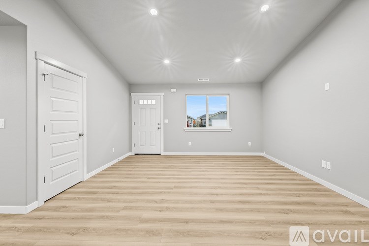 A spacious room with wooden flooring and white walls.
