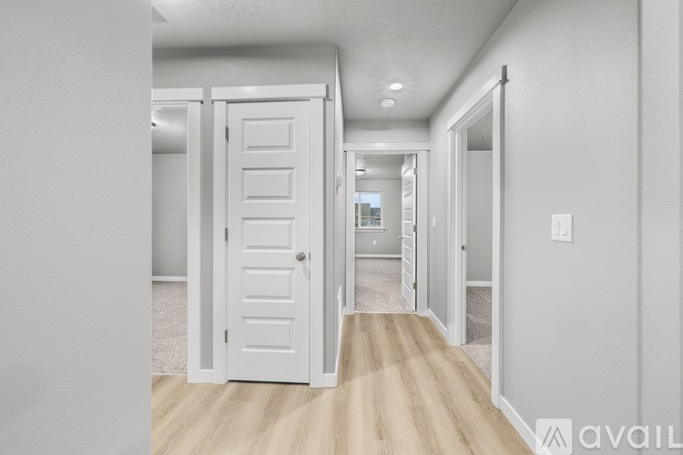 A hallway with a white door and a carpeted floor.