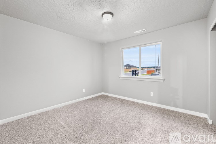 A room with a carpeted floor and a window showing a view of buildings outside.