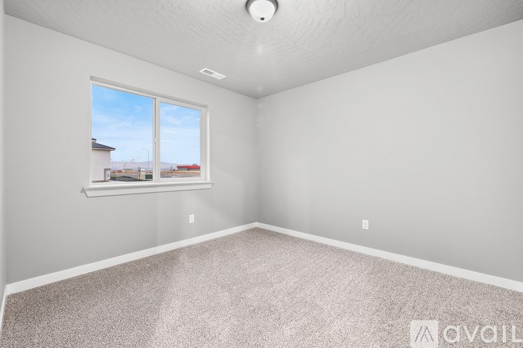 A room with a window and a carpeted floor.