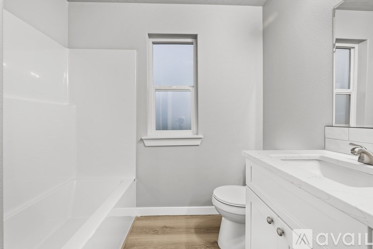 A white bathroom with a toilet, sink, and window.