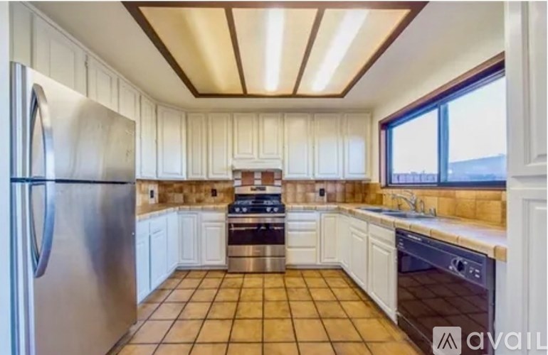 A kitchen with white cabinets and a stainless steel refrigerator.