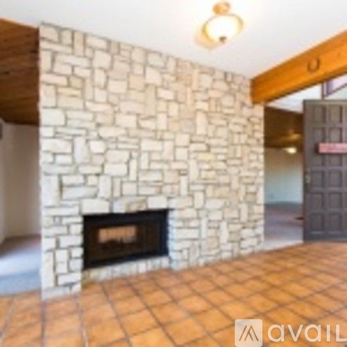 A stone fireplace in a room with tiled flooring.